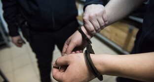Сотрудник полиции держит за руку задержанного. Фото Елены Синеок, "Юга.ру"