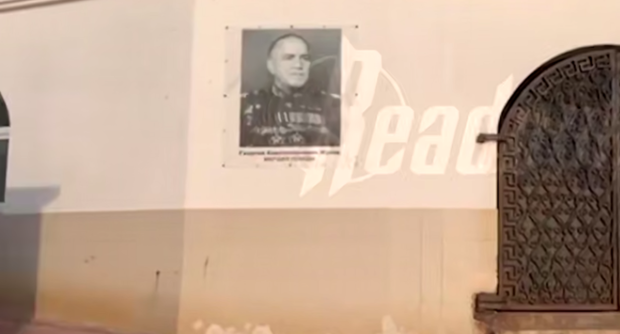 Место рядом с портретом Жукова, где ранее висел потрет Рамзана Кадырова, пустует. Стоп-кадр видео Readovka от 29.07.25, https://t.me/readovkanews/99255