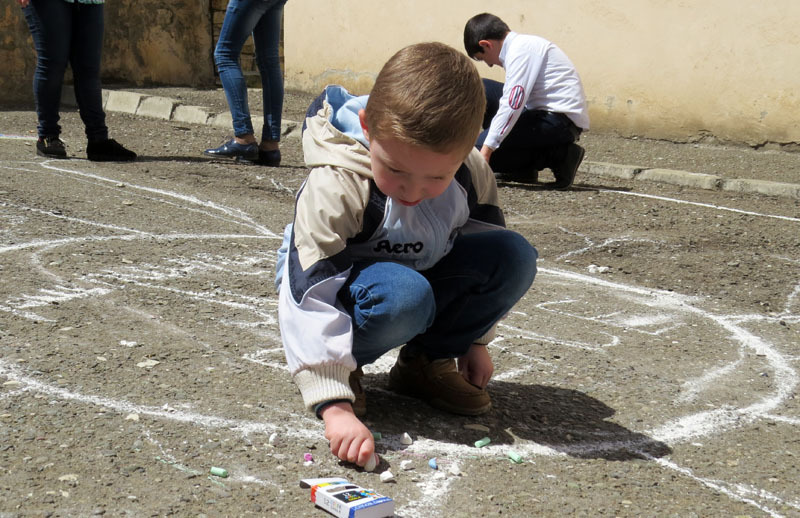 А какой-то совсем мелкий, точно, пока не школьник, пытался на асфальте мелком что-то нарисовать