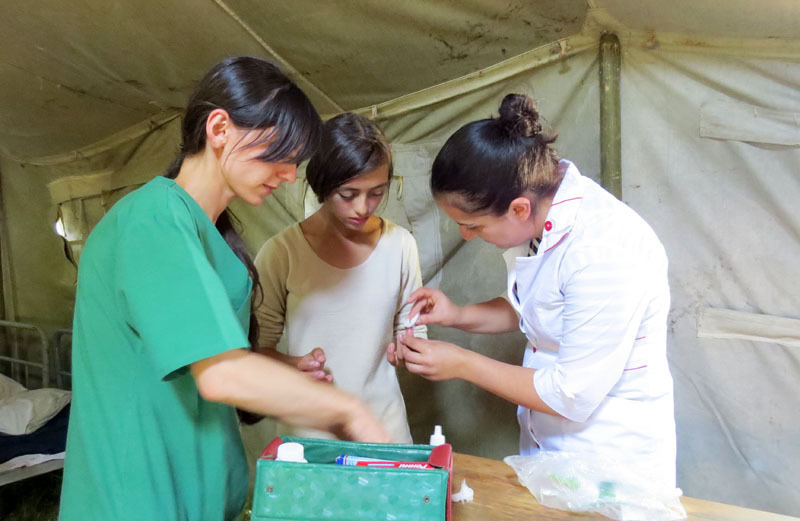 В этот момент в медпункт, недалеко от моего местонахождения, подошла скаут Люда с окровавленным пальцем – порезала ножом, когда чистила на кухне картошку. Медсёстры Стелла (слева) и Эмма сразу же сделали ей перевязку. В этот момент в медпункт, недалеко от моего местонахождения, подошла скаут Люда с окровавленным пальцем – порезала ножом, когда чистила на кухне картошку. Медсёстры Стелла (слева) и Эмма сразу же сделали ей перевязку.